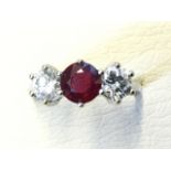 An 18ct gold ruby & diamond ring, the circular claw set ruby of 1.8 carats flanked by two