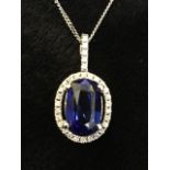 An 18ct sapphire & diamond pendant, the oval claw set sapphire weighing four carats, framed by a