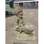 A large composition stone garden gnome birdbath, the bearded fellow pushing a wheelbarrow on plinth.