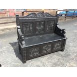 A Victorian carved oak settle, the back with armorial arched crest framed by acanthus leaf panels