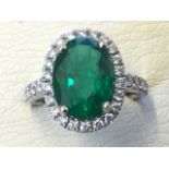 An 18ct gold Zambian emerald & diamond cluster ring, the oval emerald weighing over three carats,