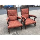 A pair of Victorian carved oak armchairs, the upholstered backs with scroll carved rails having knob