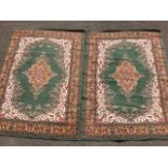 A pair of Shiraz style rugs woven with oval scrolled medallions and spandrels on green fields, the