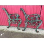 A pair of cast iron bench ends with pierced scrolled frames having lionhead terminals, raised on
