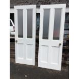 A pair of painted Victorian panelled doors with later frosted glazing to top, both mounted with