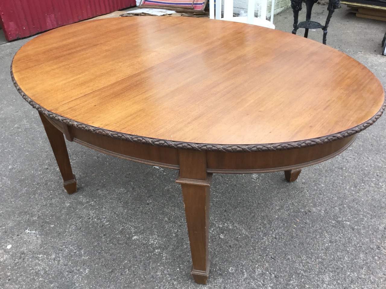 A late Victorian mahogany dining table, the oval top with flowerhead carved edge above a plain