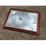 A contemporary mirror with bevelled plate in press moulded mahogany frame. (33in x 24in)