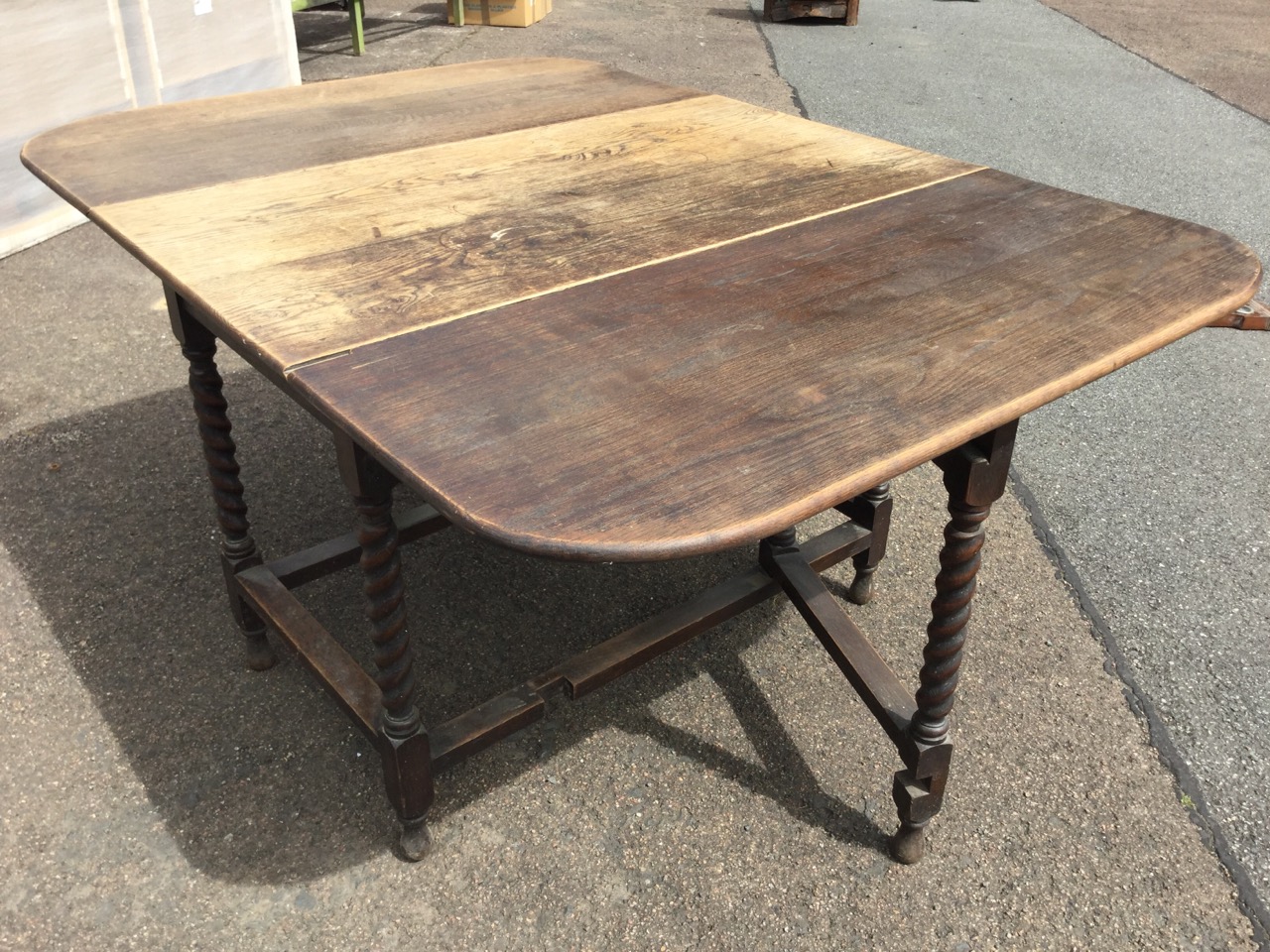 An oak dining table, the rectangular top with rounded drop leaves on barleytwist supports joined