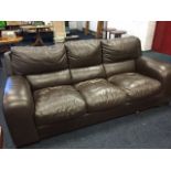 A large leather upholstered three-seater sofa with panelled cushions, raised on block feet. (86in