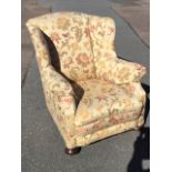 An Edwardian wing armchair, upholstered in William Morris style tapestry material, having padded