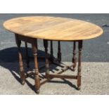 An oval oak drop-leaf dining table raised on baluster turned legs joined by rectangular