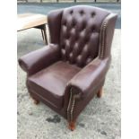 A Georgian style button upholstered gentlemans wing armchair with brass studding, having wide arms