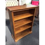 An oak open bookcase with rectangular top above four shelves framed by fluted stiles, raised on