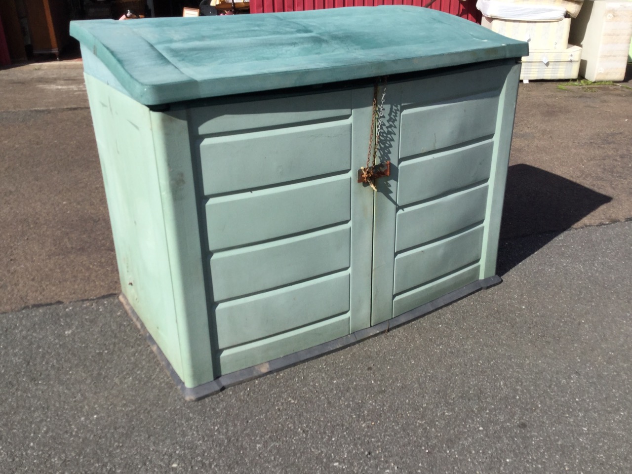 An outdoor storage cabinet with angled roof and two doors, the interior wired for electricity. (57.