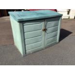 An outdoor storage cabinet with angled roof and two doors, the interior wired for electricity. (57.