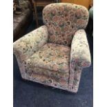 A 1950s upholstered armchair with original fabric, having rounded back above a sprung upholstered