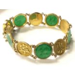 An 18ct gold Chinese bracelet, with alternating circular panels of characters & jade medallions