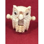 A carved bone tape measure modelled as an owl inlaid with glass bead eyes, the tape on roller with