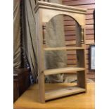 A hanging pine plate rack with moulded cornice above an arched apron on turned spindles, with