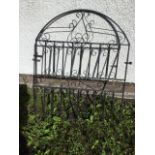 An arched wrought iron garden gate with scroll decorated panels. (38in x 46.25in)