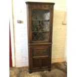 A carved oak corner cabinet with moulded cornice above a frieze with arched flowerheads, the