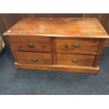 A rectangular blanket box style chest with four drawers mounted with cup handles, raised on