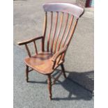 A nineteenth century elm lathback farmhouse armchair, having shaped arms on turned spindles above