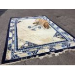 A Chinese carpet woven with circular blue floral medallion and spandrels on ivory field, framed by