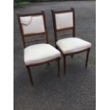 A pair of mahogany side chairs with upholstered back panels in reeded frames above spindles, the