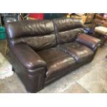 A brown leather sofa with loose cushions and padded arms, raised on ribbed block feet. (76in x