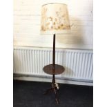 A mahogany standard lamp with turned fluted column on tripartite legs, having mid-tier circular tray