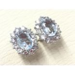 A pair of 18ct white gold aquamarine & diamond earrings, the oval claw set stones weighing over