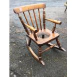A Victorian childs rocking chair, with spindle back above an elm seat, raised on angled turned