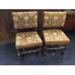 A pair of antique oak floral woolwork tapestry covered side chairs, the bobbin turned legs joined by