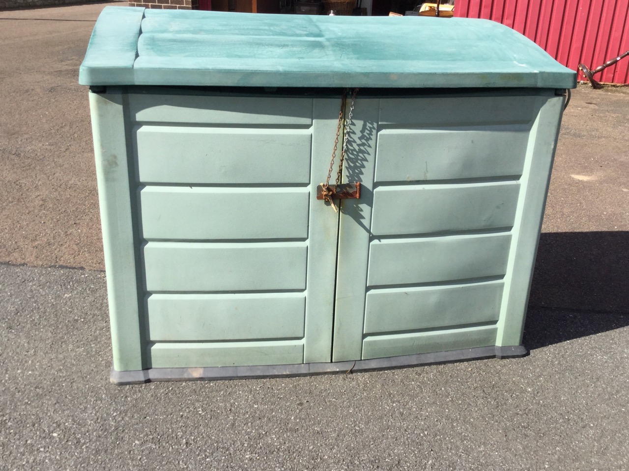 An outdoor storage cabinet with angled roof and two doors, the interior wired for electricity. (57. - Image 2 of 3