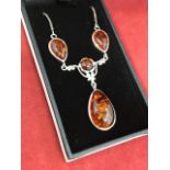 An amber mounted pendant necklace with thee teardrop shaped panels around a central circular