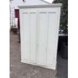 A Victorian painted cupboard with moulded cornice above twin panelled doors enclosing shelves,