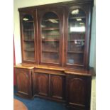 A Victorian mahogany bookcase, the rounded top with three arched glazed doors enclosing adjustable