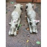 A pair of composition stone greyhounds, lying in prone positions with heads between their paws,