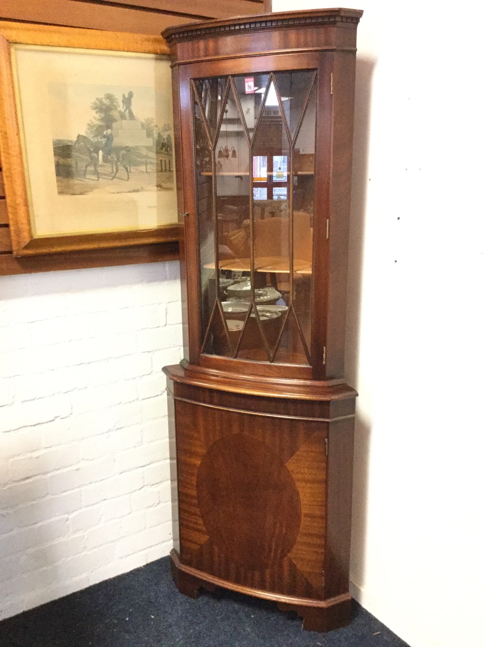 A bowfronted mahogany corner cabinet with moulded dentil cornice above an astragal glazed door