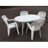 A rectangular rounded garden dining table with four armchairs, the top with hole for shade, raised