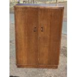 An oak compactum with caddy top above cockbeaded doors enclosing a fitted interior with hanging