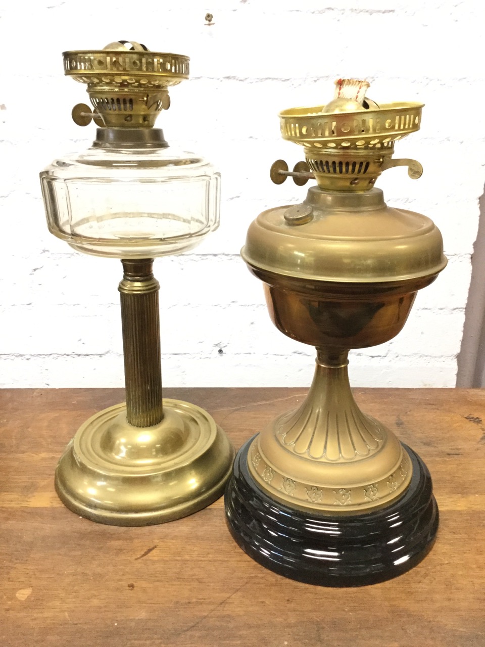 A Victorian brass oil lamp with chamfered bun shaped glass reservoir on fluted column above weighted