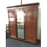 A Victorian mahogany combination wardrobe, with cushion moulded cornice above three rounded panelled