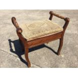 A stained piano stool with rectangular tapestry upholstered lifting seat flanked by turned