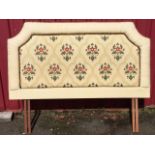 An upholstered double headboard with floral padded panel in pleated cushion upholstered border