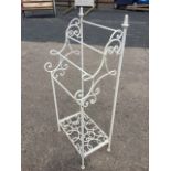 A wrought iron towel stand with four rails on scrolled supports with leaf cast finials, the square