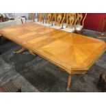 An expanding walnut dining table with two spare leaves, the crossbanded top with segmented geometric