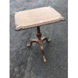 A mahogany occasional table, the rectangular top with leaf carved edge supported on a vase turned