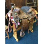 A western leather saddle overall embossed with floral panels having brass mounts, with cushion seat,